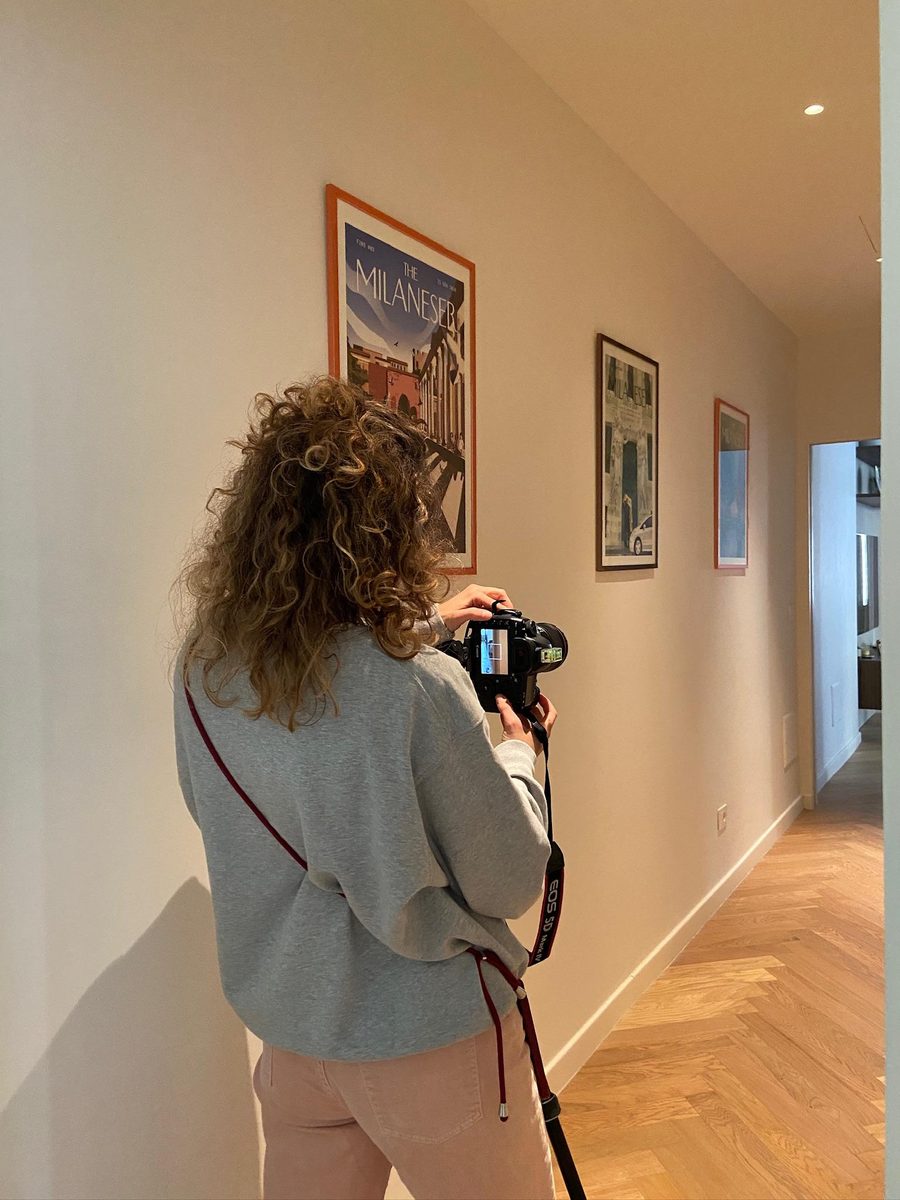 Marta di spalle mentre inquadra una parete di quadri